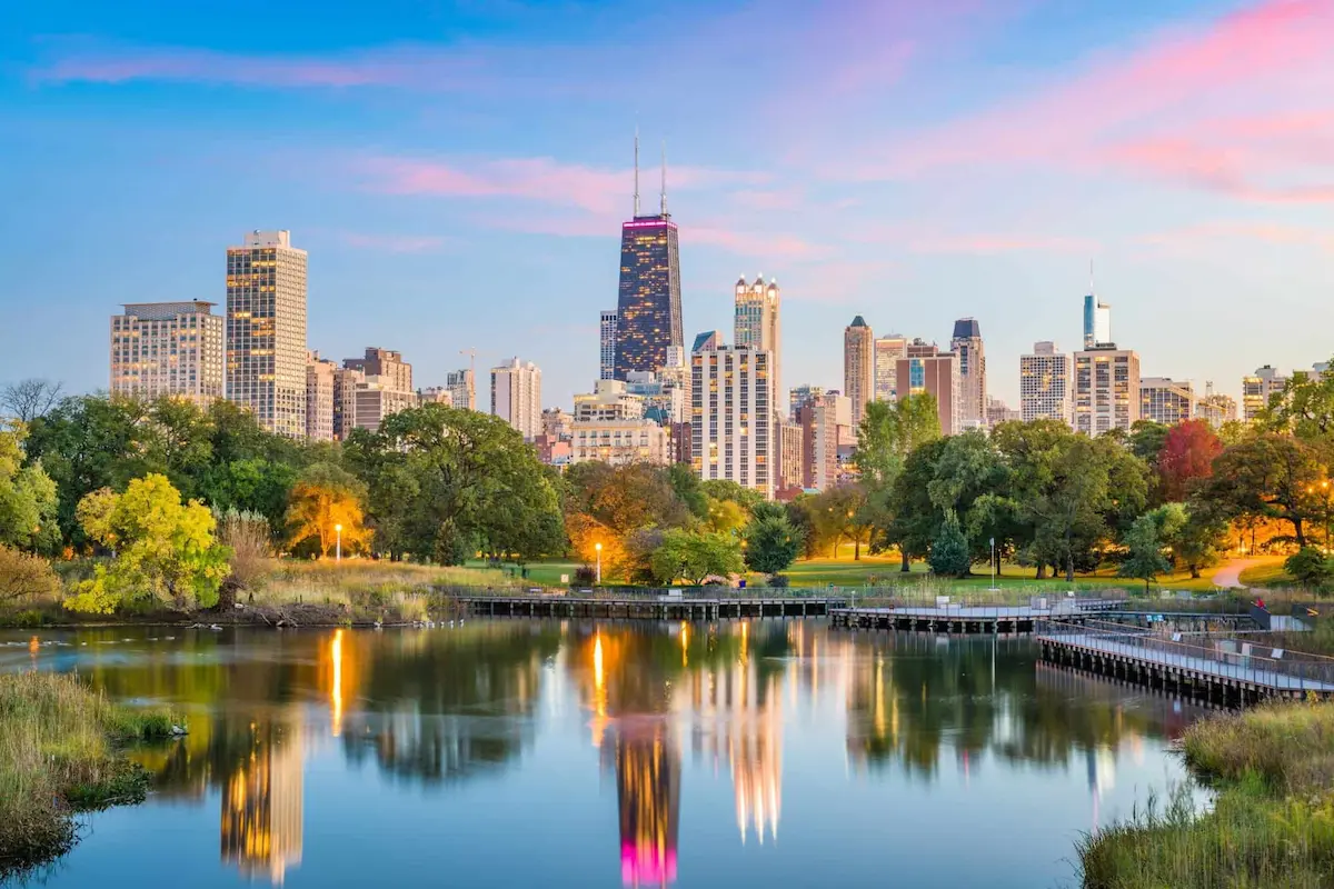 Chicago skyline reflected on a lake during sunset.