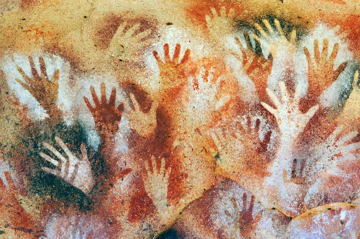 Ancient cave wall with colorful prehistoric human handprints