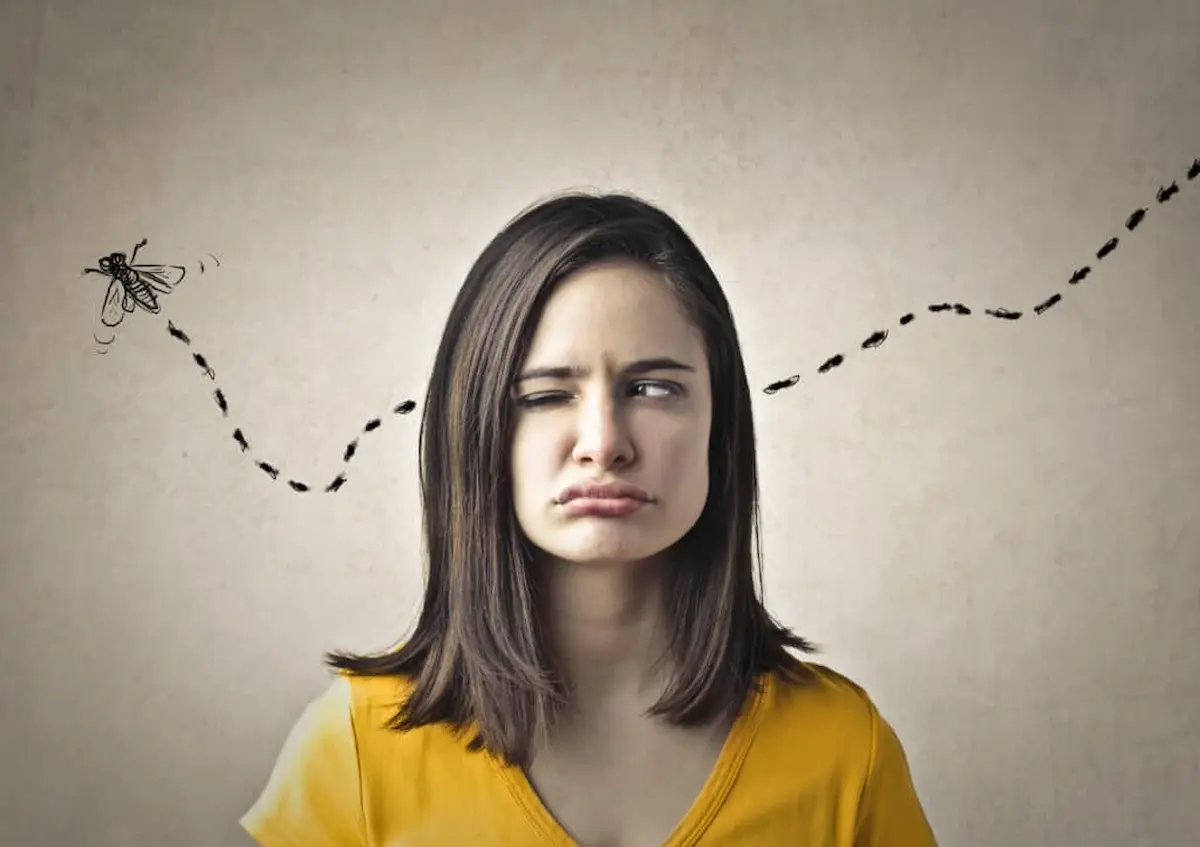 Frustrated woman watching a flying insect with a dotted flight path illustrated behind her