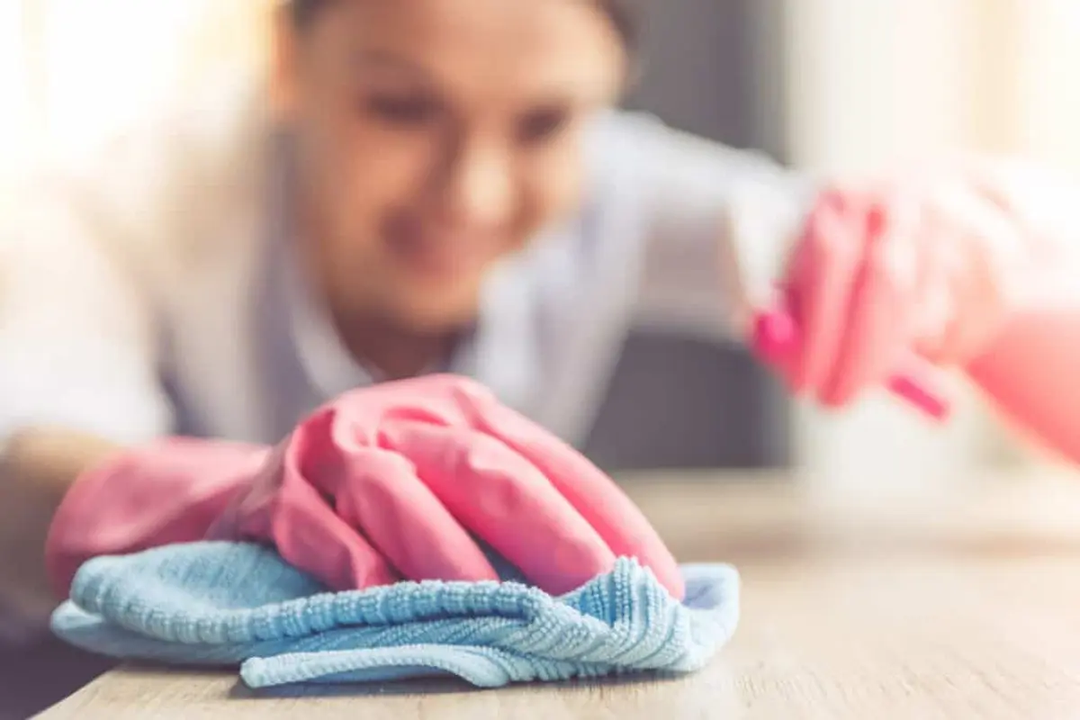 Person cleaning a surface with spray and cloth