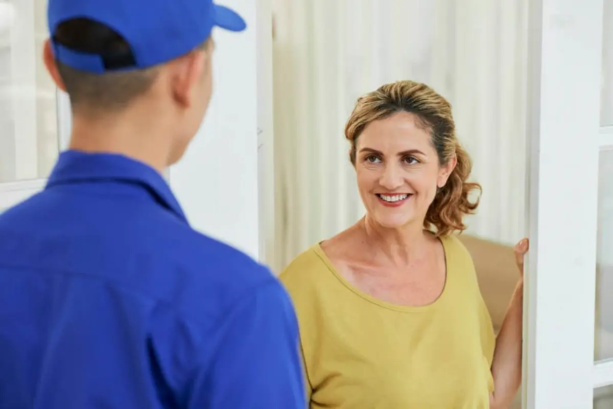 Professional pest control technician speaking with a homeowner at the front door before providing pest inspection or treatment services.