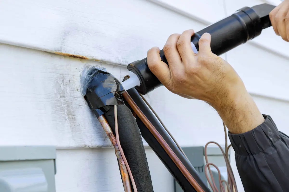 Applying sealant around exterior utility pipes to help prevent pest entry into a home