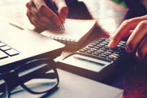 shutterstock 566835985 Close,Up,Woman,Hand,Using,Calculator,And,Writing,Make,Note