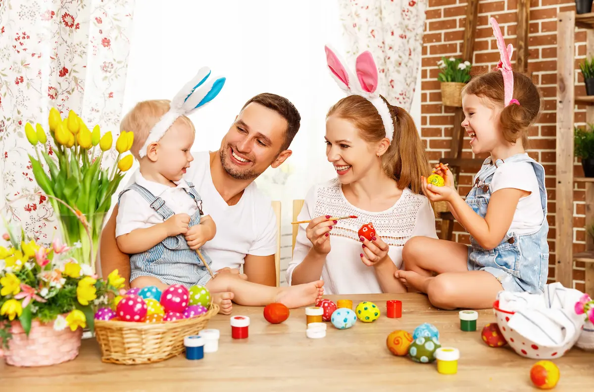 Happy family with children painting colorful Easter eggs indoors