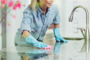 shutterstock 722926426 Pedantic,Woman,Wiping,Down,Kitchen,Countertop,With,Pink,Cloth,,Wearing
