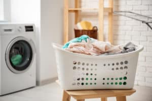 shutterstock 778355935 Basket,With,Laundry,On,Stool,And,Washing,Machine,In,Bathroom
