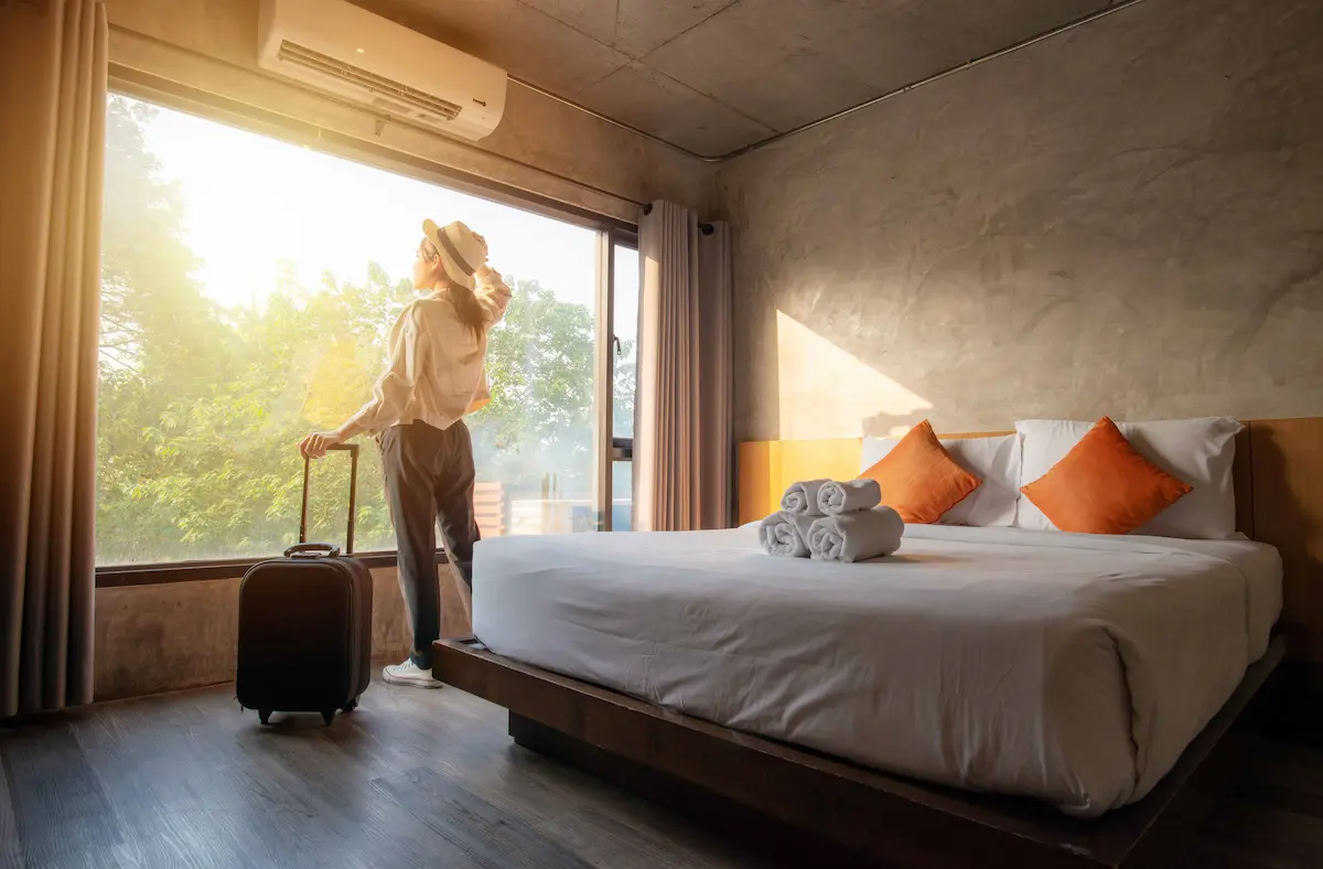 Traveler standing in a hotel room with luggage and enjoying the view