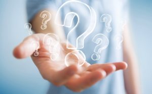 nbvcx Businessman on blurred background holding hand drawn question marks