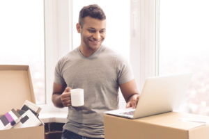shutterstock 518934208 Handsome,Man,Is,Using,A,Laptop,,Holding,A,Cup,And