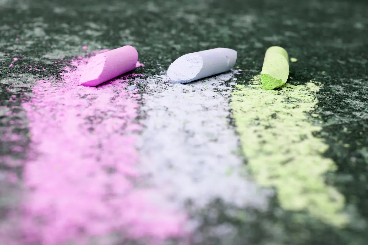 Broken colored sidewalk chalk with powder on a dark surface