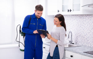 shutterstock 1315343546 Young,Male,Pest,Control,Worker,Showing,Invoice,To,Woman,In