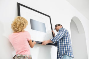 shutterstock 598929419 Couple,Hanging,Picture,Frame,On,Wall,In,New,House