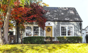 shutterstock 755857687 Beautiful,Grey,Wood,Shingle,Cottage,With,Autumn,Trees,And,Wreath