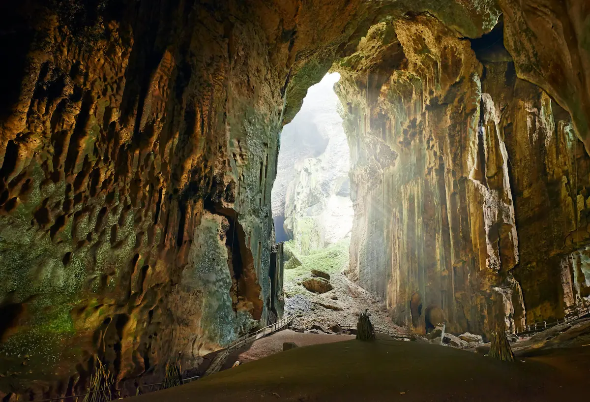 Massive cave interior with rock formations and natural light opening